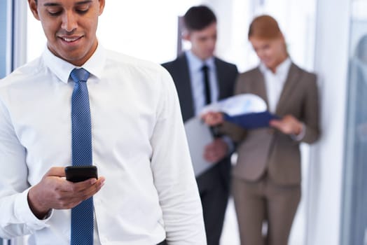 Young businessman with cellphone reading sms in working environment