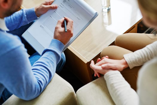 Male psychiatrist making notes with his patient near by