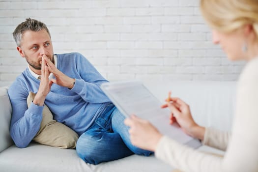Thoughtful man sitting on sofa in front of his psychologist