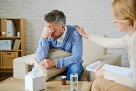 Despaired man with pillow and handkerchief being reassured by his psychologist