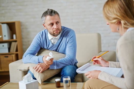 Despaired man with pillow and handkerchief looking at his psychologist during consultation