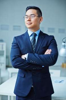 Young Asian businessman in suit crossing his arms