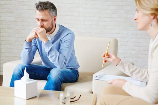 Sad man sitting by his psychologist