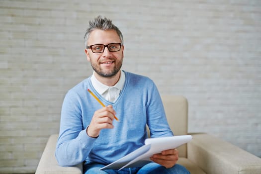 Male psychiatrist with pencil and clipboard looking at camera