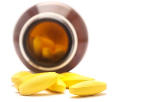 Pills spilling out of a bottle isolated on white background, Selective focus