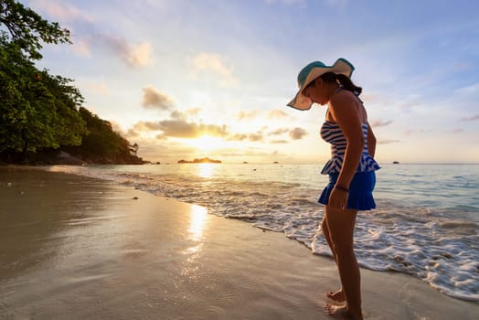 Girl in a swimsuit standing sand and water play with happiness during sunrise on the beach of Honeymoon Bay at Koh Miang, Similan Islands National Park, Phang Nga, Thailand