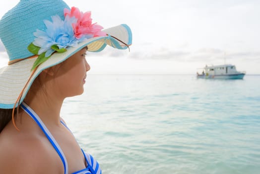 Half portrait teenage girls in a blue swimsuit looking beautiful nature of sea during sunrise with happiness on beach at Koh Miang Island, Similan National Park, Phang Nga, Thailand