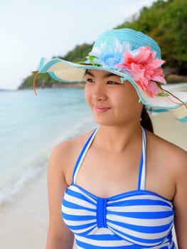 Half portrait teenage girls in a blue swimsuit looking beautiful nature of sea during sunrise with happiness on beach at Koh Miang Island, Similan National Park, Phang Nga, Thailand