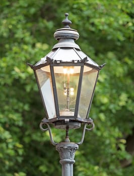Old gas lantern lights up during the day