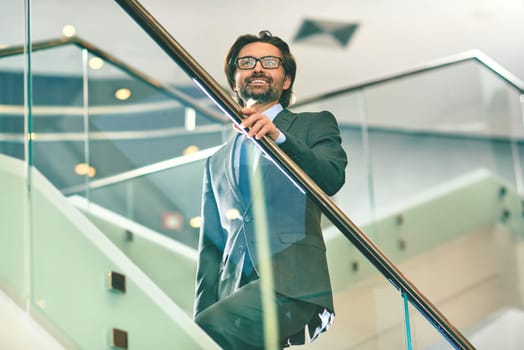 Mature businessman going upstairs inside office building