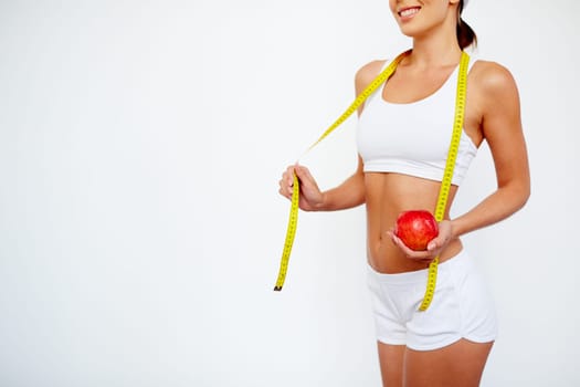 Slender girl with apple and measuring tape standing in isolation
