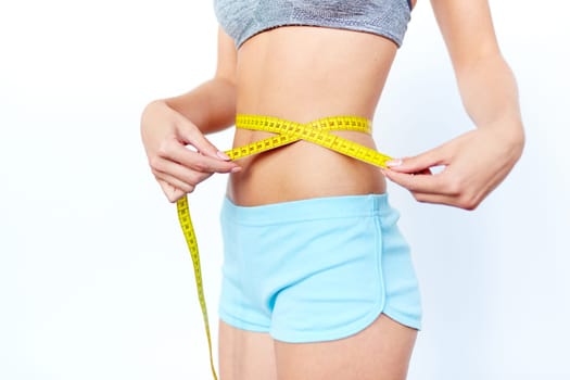 Waist of slim female being measured with tape