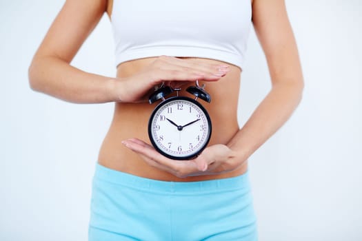 Slender female holding alarm clock between her palms