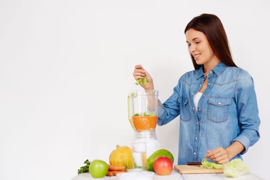 Pretty girl making smoothie from fresh vegetables