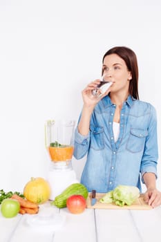 Young female drinking water by table with vegetables