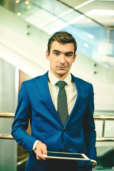 Well-dressed businessman with touchpad looking at camera