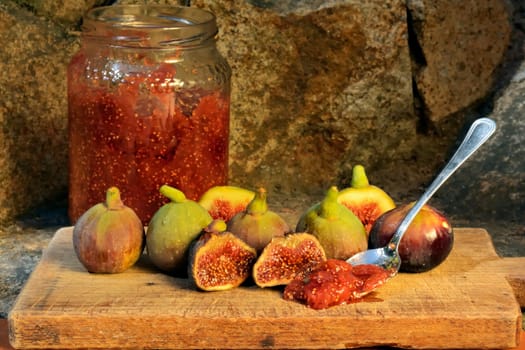 Composition of fig fruits on a wooden board and rocks in the background.