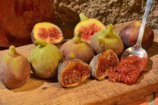 Composition of fig fruits on a wooden board and rocks in the background.