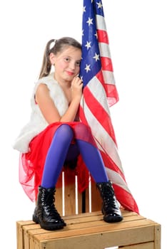 a pretty little girl sitting on a box with a american flag on the white background