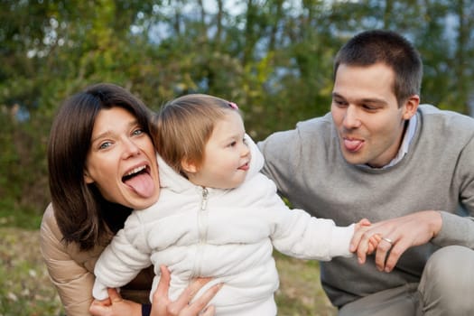 Mother Father and their little baby having happy times together in autumn outdoor in the green wood and grass