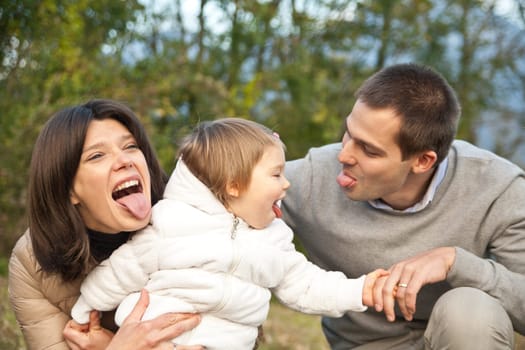 Mother Father and their little baby having happy times together in autumn outdoor in the green wood and grass