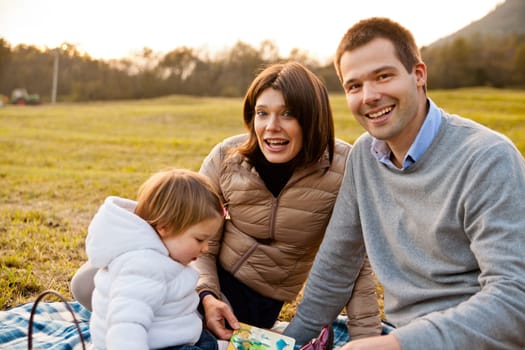 Mother Father and their little baby having happy times together in autumn outdoor in the green wood and grass