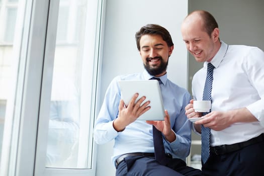 Handsome employee with touchpad explaining data to his colleague