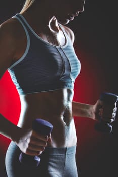 Young female doing exercise with dumbbells and sweating