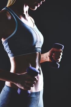 Slim woman with dumbbells doing physical exercise