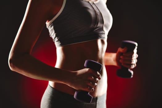 Female torso in activewear during exercise with dumbbells