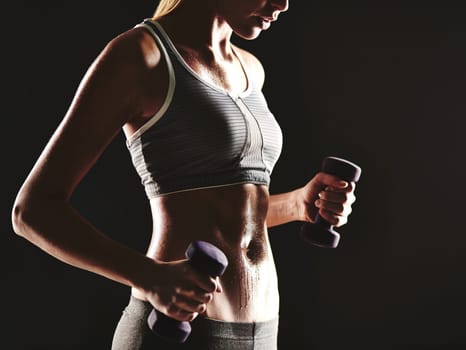 Young female training with dumbbells in isolation