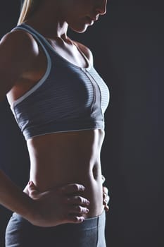 Body of slim female in activewear keeping her hands on waist