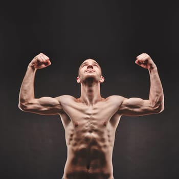 Strong young man looking upwards with raised arms in isolation