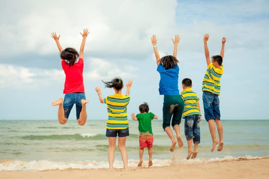 Happy family jumping at the beach at the day time