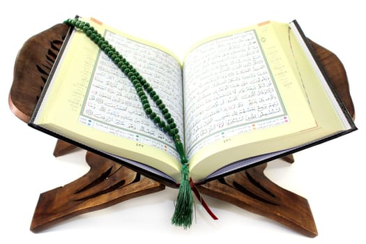 Quran with wooden Koran stand against a white background