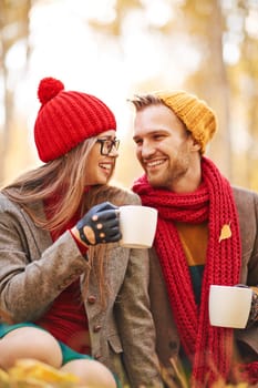 Amorous young couple talking and laughing while drinking tea in natural environment