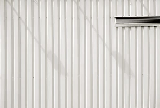 A modern facade of a shopping centre and tree market made of corrugated sheet with a ventilation slot and shade.
