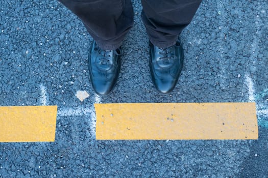 2 shoes and legs with yellow marking on the floor