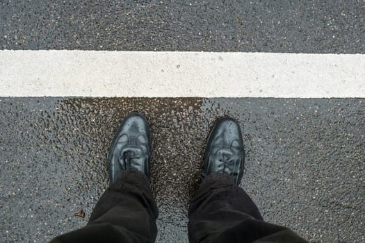 Legs with shoes on wet ground with white stripes