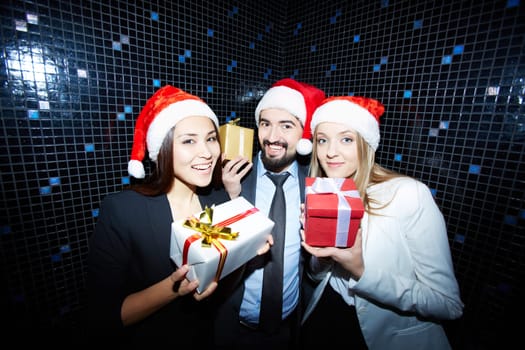 Cheerful business group in formalwear and Santa caps showing their presents