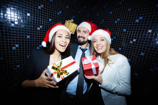 Cheerful businesspeople in Santa caps showing their presents in packages