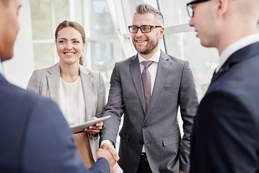 Happy colleagues looking at their business partner while greeting him