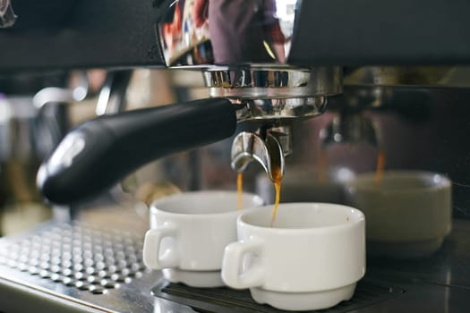 Espresso pouring in two porcelain cups from coffee machine