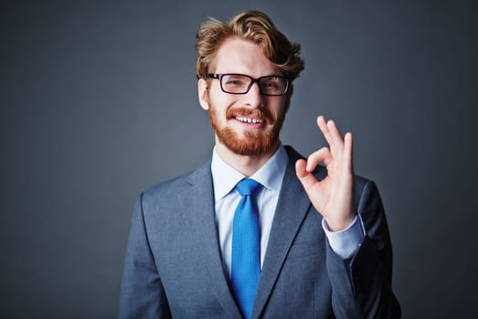 Happy businessman in eyeglasses and suit showing okay sign
