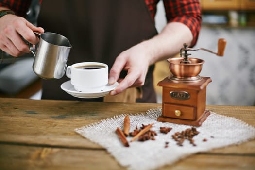 Hands of barista holding cup black coffee and steel mug