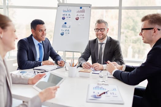 Group of confident co-workers consulting at meeting in office