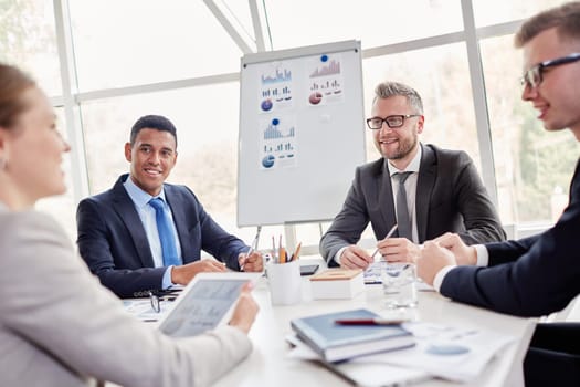 Group of confident employees listening to their colleague at meeting in office