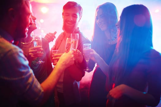 Cheerful friends toasting with champagne in night club