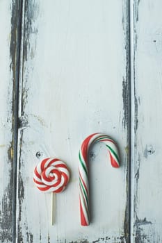 Sweet lollipop and candy cane on wooden background