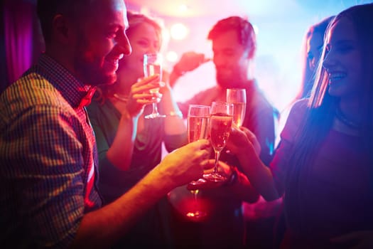 Group of happy friends toasting at party with champagne